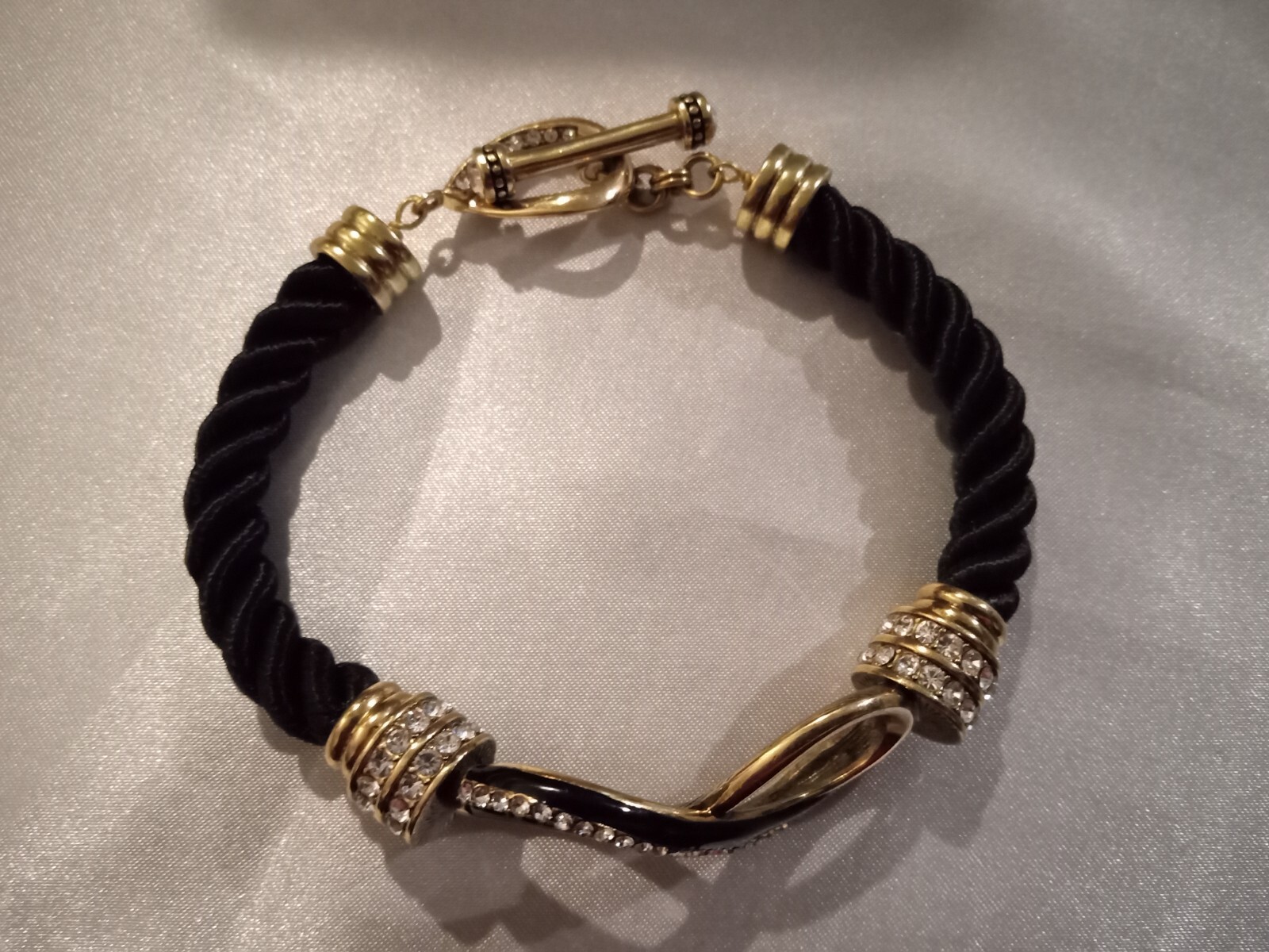 HEIDI DAUS GOLD TONE/BLACK ROPE/CRYSTAL FIGURE 8 BRACELET 8″