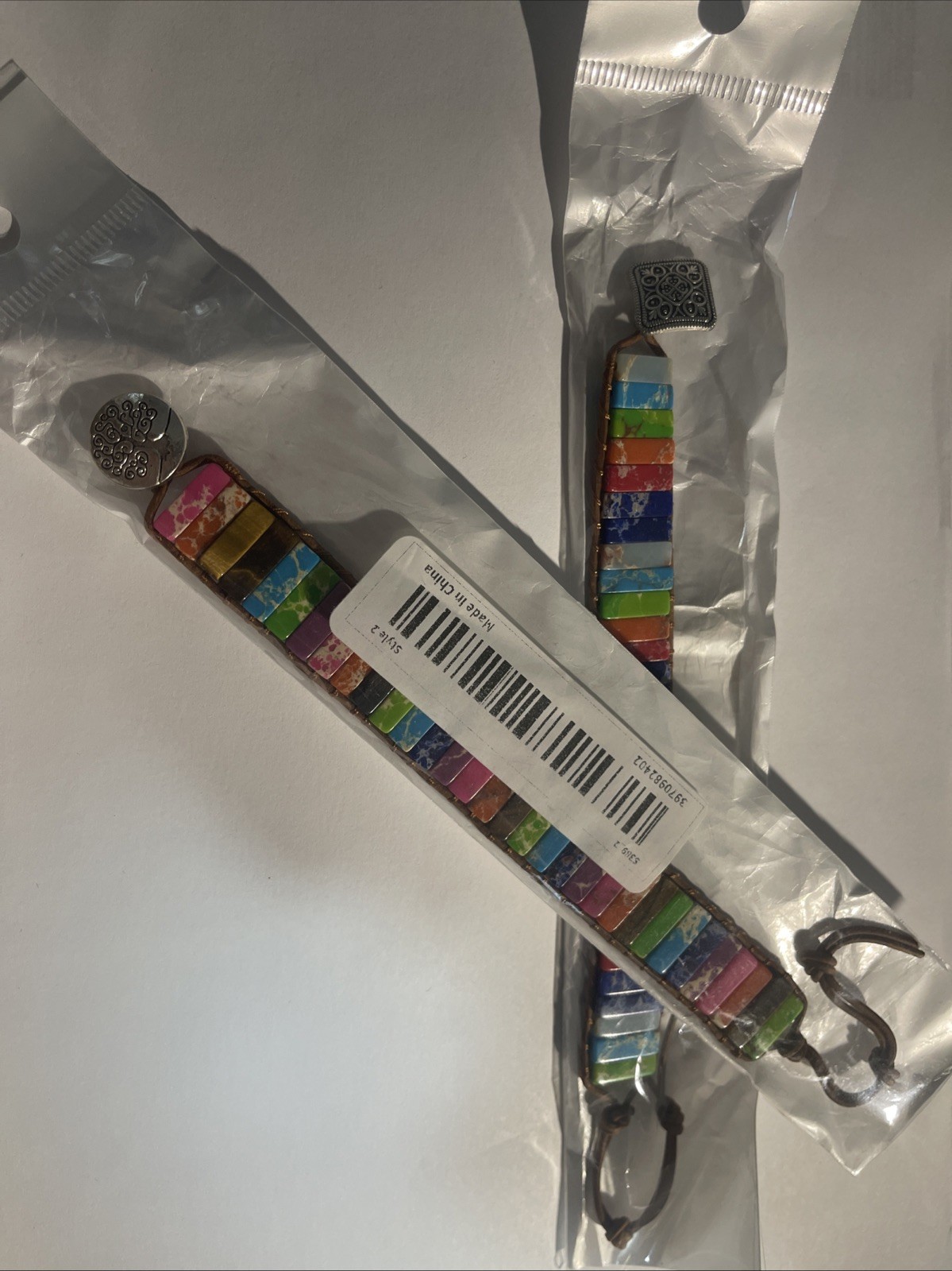 Set of 2 multicolored stone bracelets with leather cord and metal clasp.